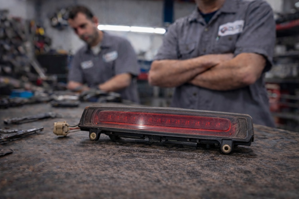 Technician inspecting used third brake light assembly